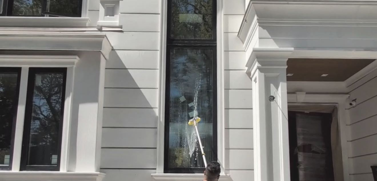 Uplift Contracting crew cleaning windows on a white two-storey home in West Vancouver